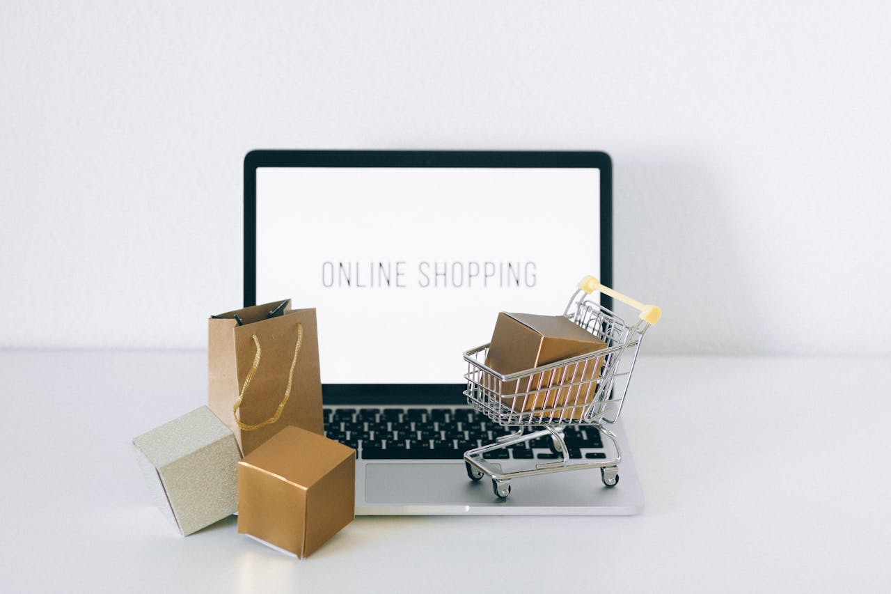 home-hero Laptop displaying online shopping with boxes and cart, representing ecommerce.
